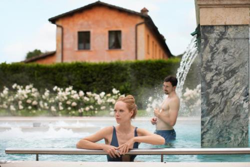 Un uomo e una donna seduti in piscina di QC Termeroma Spa and Resort a Fiumicino