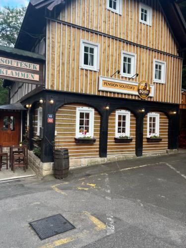 un grande edificio in legno con un cartello sopra di Pension Soutěsky a Hřensko