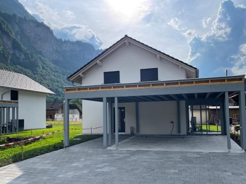 ein weißes Haus mit einer Garage mit Bergen im Hintergrund in der Unterkunft Villa Sofie in Meiringen