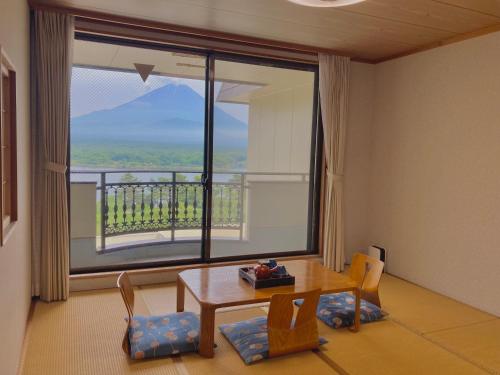 um quarto com uma mesa e cadeiras e uma grande janela em Shoji Mount Hotel em Fujikawaguchiko