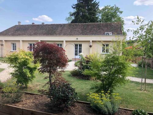 uma casa branca com árvores e arbustos à sua frente em Riverside Lodge em Chablis