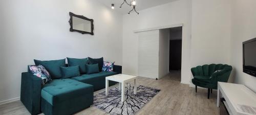 uma sala de estar com um sofá azul e duas cadeiras verdes em Apartament CityStation em Wałbrzych