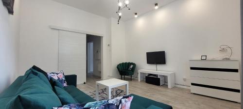 uma sala de estar com um sofá verde e uma televisão em Apartament CityStation em Wałbrzych