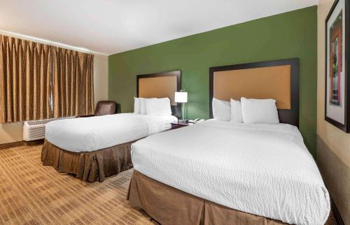 duas camas num quarto de hotel com paredes verdes em Extended Stay America Suites - Indianapolis - Airport em Indianápolis