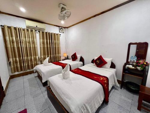 um quarto com três camas e um espelho em Nocknoy Lanexang Guest House em Luang Prabang