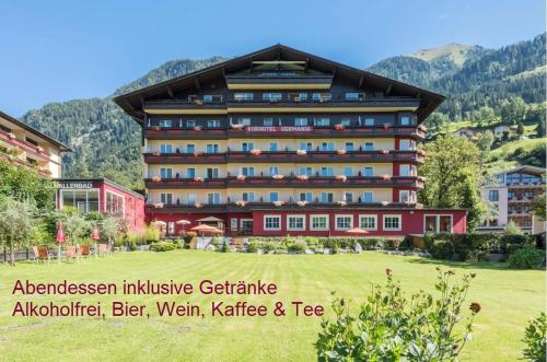 Hotel Germania Gastein - ganzjährig inklusive Alpentherme Gastein & Sommersaison inklusive Gasteiner Bergbahnen في باد هوفغاستين: مبنى كبير أمامه حقل أخضر