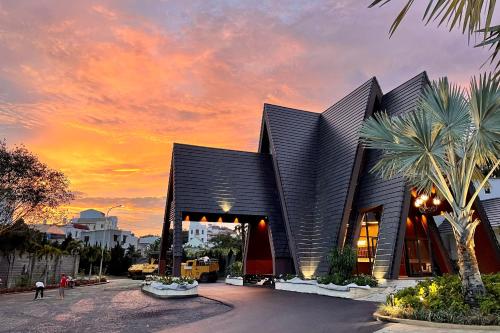 a building with a palm tree in front of a sunset at Sunflower Hotel & Resort in Bao Loc