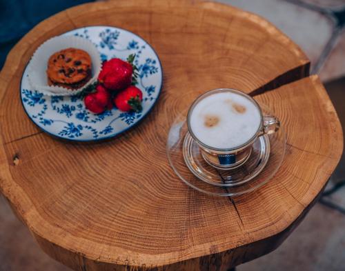 a table with a cup of coffee and a plate of strawberries at Willa Skalniak in Lądek-Zdrój