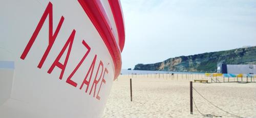 a surfboard on a beach with a volley ball court at Rancho Tá-Mar Apartment Nazaré Beach in Nazaré