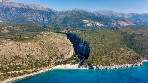 an aerial view of a beach with mountains in the background at Blu Horizon Hotel Gjipe in Dhërmi