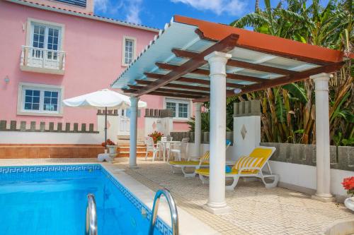 una piscina con pérgola y una casa rosa en Villa House Joana Vasconcelos, Ocean view & Pool - Pata da Gaivota, en Lourinhã