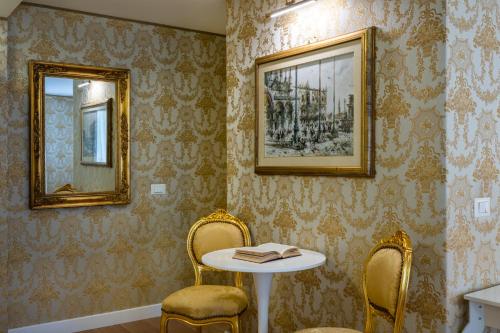 une chambre avec deux chaises, une table et deux miroirs dans l'établissement Hotel Apostoli Garden, à Venise