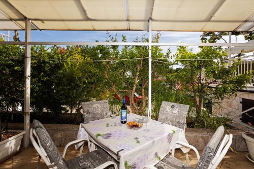 una mesa blanca y sillas con una botella de vino en Balic Apartments - Hvar, en Hvar