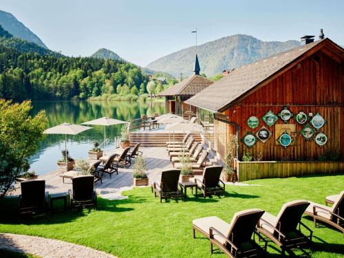 Seehotel Grundlsee في غروندلسي: مجموعة كراسي ومبنى بجانب البحيرة