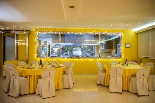 een eetkamer met tafels en stoelen met gele muren bij Hotel Residence Federiciano in Valenzano