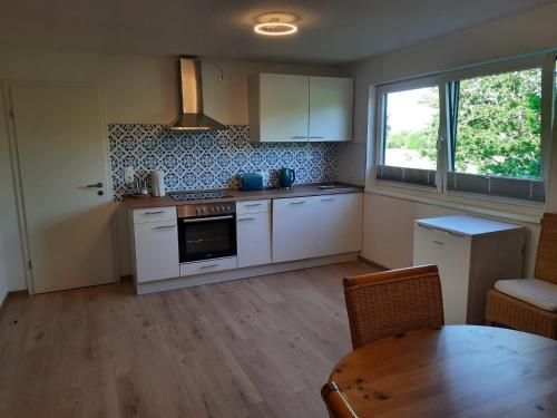 a kitchen with white cabinets and a table and a window at Ferienwohnung Rosi in Schleswig