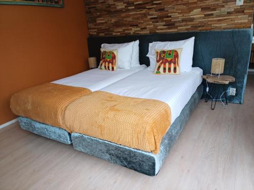 um quarto com 2 camas individuais, almofadas e uma parede de tijolos. em East Meets West Bed and Breakfast em Veenendaal