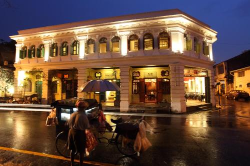 una persona con un ombrello di fronte a un edificio di Coffee Atelier a George Town