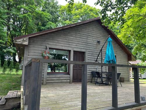 a small cabin with a deck with a blue umbrella at Vecliepas in Vārve