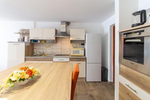 een keuken met een houten tafel en een vaas met bloemen bij Déli Terasz A Apartman Free parking, self-check-in anytime in Győr