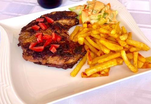 um prato com bife e batatas fritas numa mesa em Trendy apartments em Entebbe