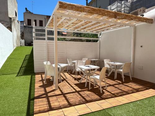 eine Terrasse mit Tischen und Stühlen unter einer Pergola in der Unterkunft Affittacamere Vicino al Porto in Porto Torres