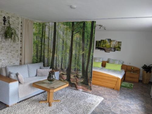 a living room with a couch and a bedroom with a forest mural at Ferienwohnung, Sauna & Gästekarte gratis im Schwarzwald in Baiersbronn