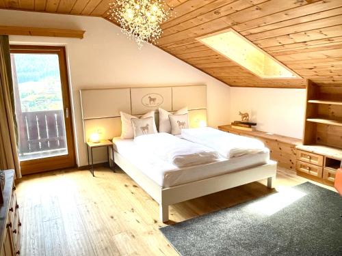 een slaapkamer met een wit bed en een kroonluchter bij Chalet Bernardi Apartments in Ortisei