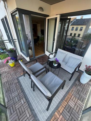 un patio con 2 sillas y un banco en el balcón en Modern Apartment - Amazing Terrace and Fjord View, Close to City Center, en Bergen