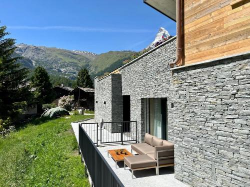 ein Steinhaus mit einem Sofa auf dem Balkon in der Unterkunft Chalet Coral und Zermatter Stadel mit Sauna in Zermatt