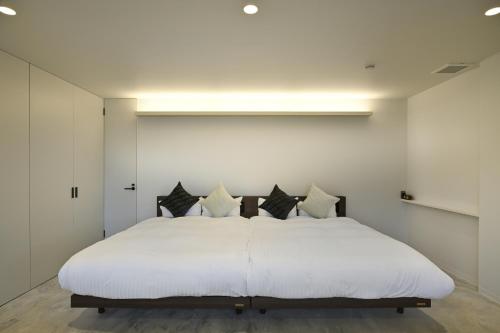 una camera da letto con un grande letto bianco con cuscini neri di Mont-モン-KAMOGAWA STAY and HOTEL a Kyoto