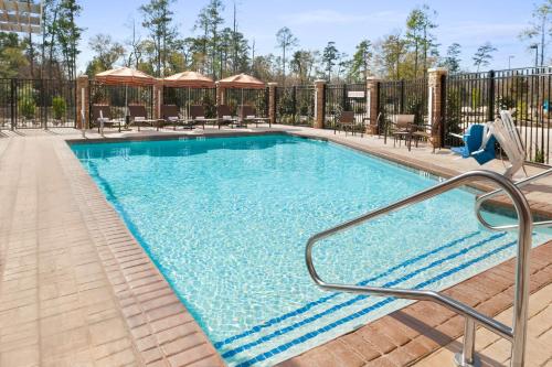 uma piscina num hotel com mesas e cadeiras em Hyatt Place Houston/The Woodlands em The Woodlands