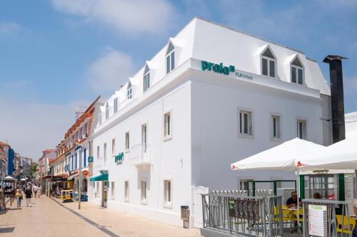 un bâtiment blanc avec un panneau dans une rue dans l'établissement Praia FLH Hotels Ericeira, à Ericeira