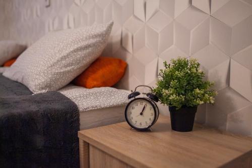 une horloge sur une table à côté d'un lit avec une plante en pot dans l'établissement Lukas Guest Rooms, à Cracovie