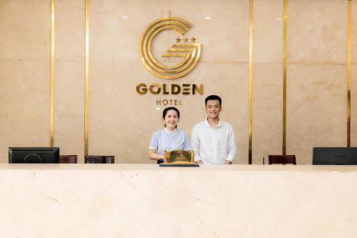 mężczyzna i kobieta stojący za ladą w obiekcie Golden Quang Tri Hotel w mieście Ðông Hà