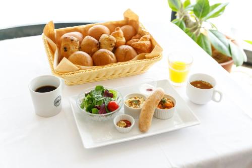 einen Tisch mit einem Teller Essen und einem Korb Brot in der Unterkunft HOTEL Third Place Hakata in Fukuoka