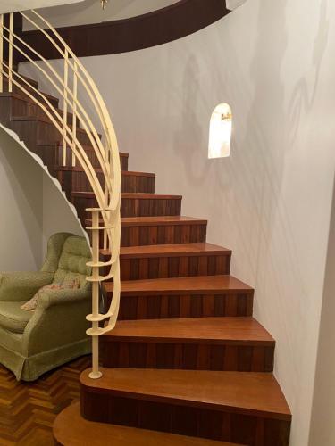 un escalier en colimaçon avec une chaise verte à côté. dans l'établissement Gracious 1930s Art Deco House, à Gosford