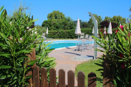 una piscina con ombrelloni e sedie e una recinzione di Agriturismo Gli Etruschi a Populonia