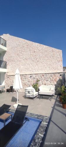 eine Terrasse mit Bänken, einem Regenschirm und einer Ziegelwand in der Unterkunft Villa merryy in Kaş