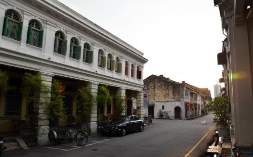 una vecchia auto parcheggiata sul lato di una strada di Coffee Atelier a George Town