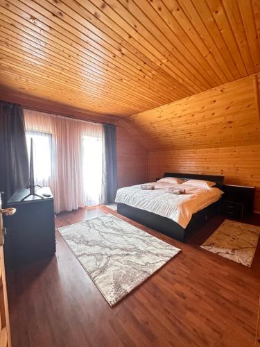 - une chambre avec un lit et un plafond en bois dans l'établissement Ollie's Mountain Chalet, à Buşteni