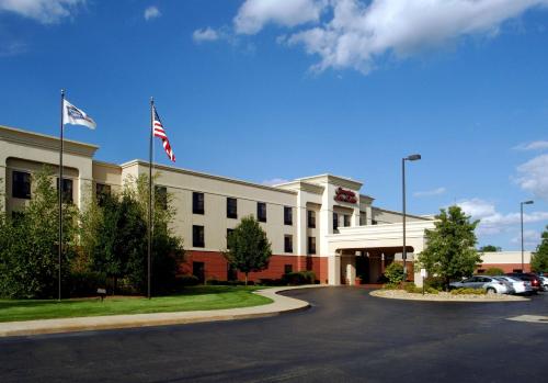 a building with two american flags in a parking lot at Hampton Inn & Suites Kalamazoo-Oshtemo in Oshtemo