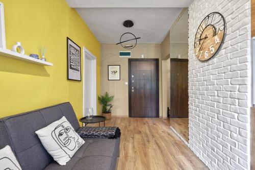 a living room with a couch and a clock on a wall at LAZUR ~ 2BD Flat next to the Sea Garden in Burgas City