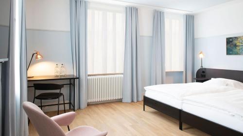 a bedroom with a bed and a desk and a chair at Hotel Schützen Rheinfelden in Rheinfelden