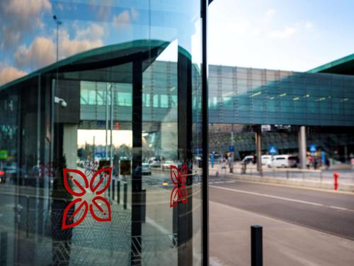 une fenêtre en verre d'un bâtiment avec des fleurs rouges sur lui dans l'établissement Hilton Garden Inn Krakow Airport, à Cracovie