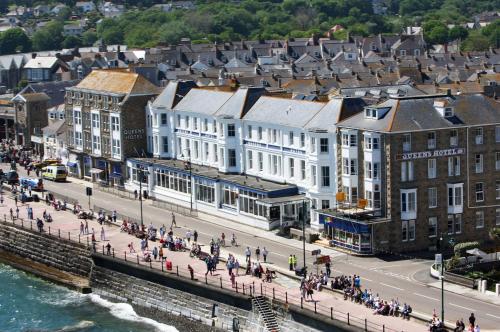 um grupo de pessoas andando em uma rua em uma cidade em The Queens Hotel em Penzance