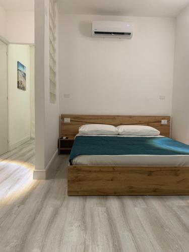 um quarto com uma cama de madeira num quarto branco em CagliariParadiseApartment it Marina em Cagliari