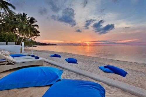 a beach with blue pillows on the sand and the ocean at La Perle Resort Koh Samui in Mae Nam