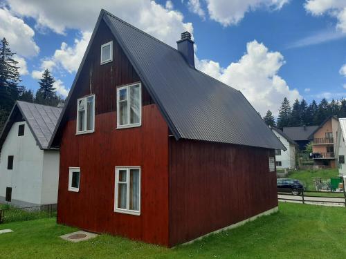 une grange rouge avec un toit noir dans l'établissement Guesthouse Durmitor Magic, à Žabljak