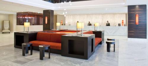 a lobby with an orange couch and stools at Hilton Mainz in Mainz